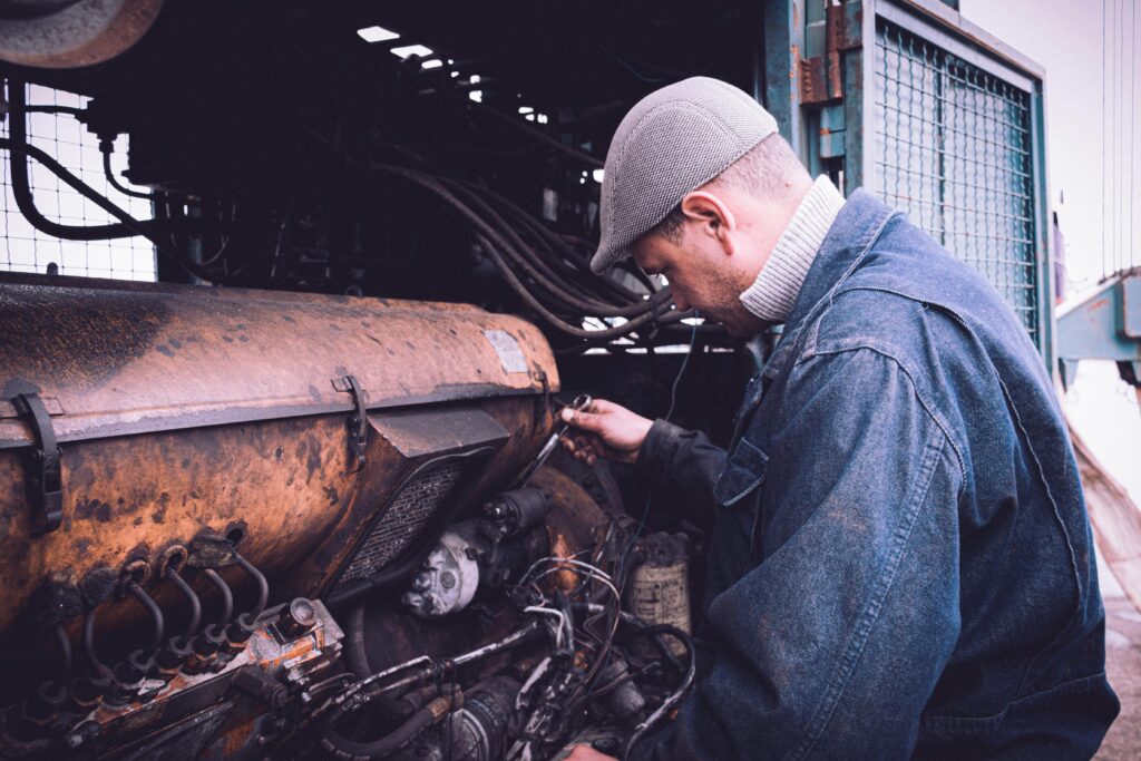 Mechanic repairs industrial engine outdoors in Tabarka, Tunisia, showcasing skilled craftsmanship.